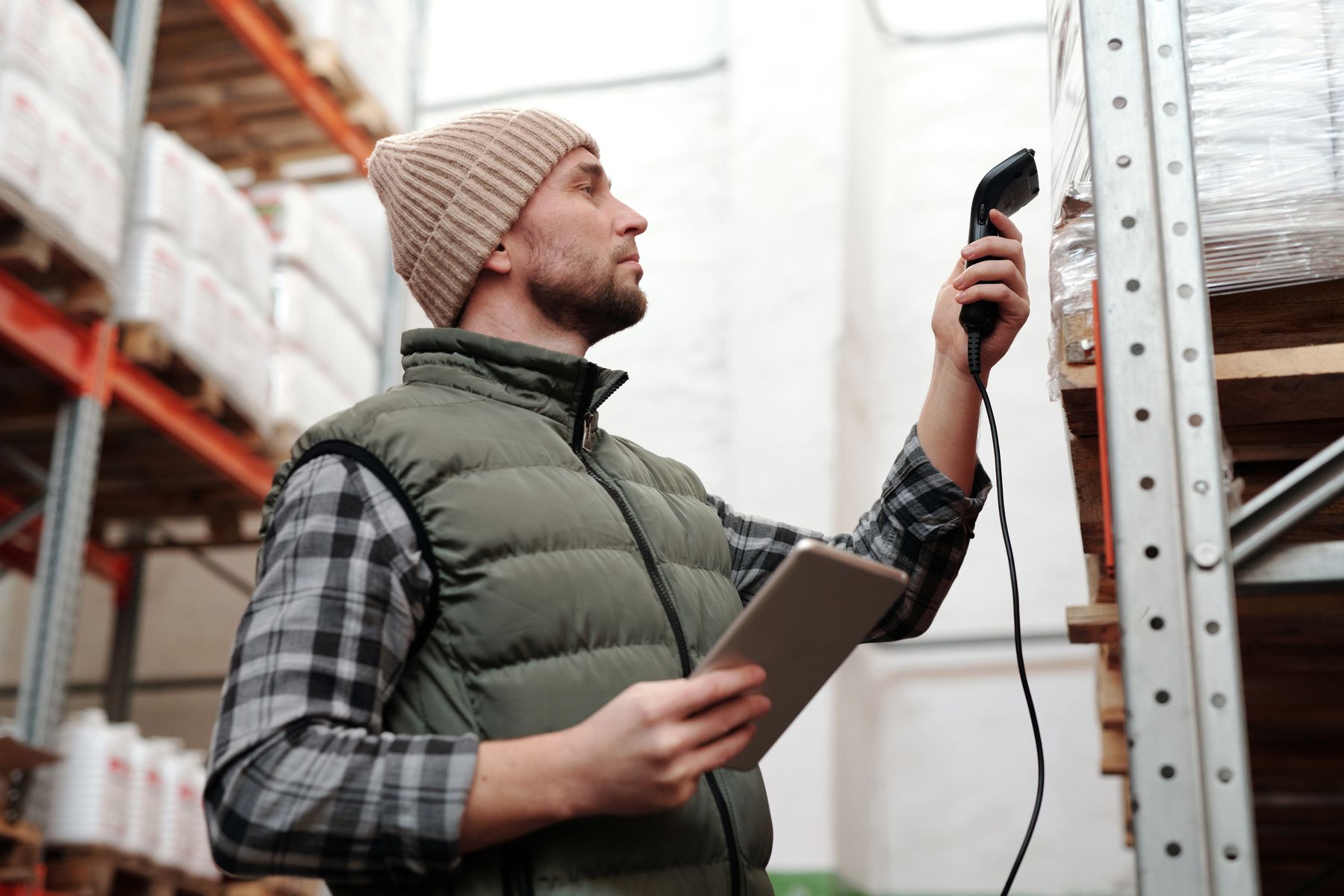 Warehouse worker using a handheld barcode scanner beside storage racks